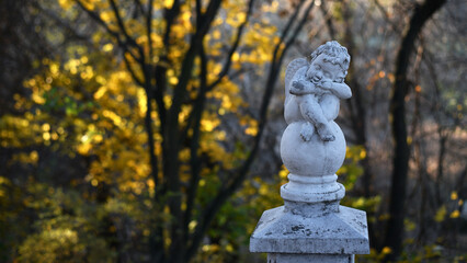 angel statue in the park. little boy with wings. cupid statue in autumn park. figurine for design,...