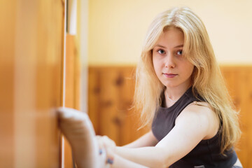 A young ballet dancer performs a stretching exercise, embracing her body and movement