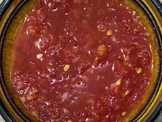 Close-up of a spicy eastern pepper seasoning presented in a deep dish. The seasoning has a bright red color with pieces of pepper and seeds.