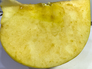 Close-up of a sliced apple with shiny yellowish flesh and clear textures.