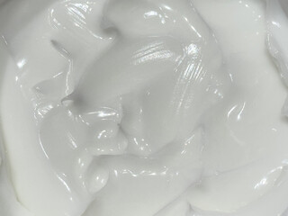 Close-up of the texture of a creamy substance that is white in color. The surface is smooth and...