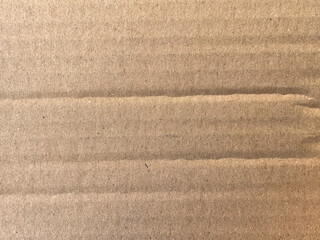 Close-up of the texture of cardboard, showcasing its surface with characteristic waves and lines. The cardboard has a light brown color, with small particles and an even texture.