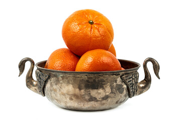 Fresh tangerines stacked in an antique metal bowl with handles on white background.
