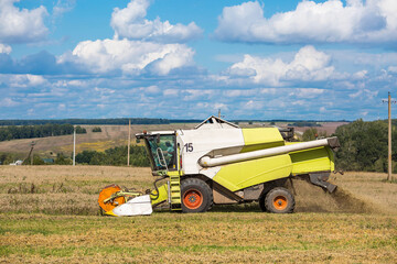 Obraz premium Agricultural industry. A combine harvester harvests from the field. The concept of processing and collection . Rural landscape. Agricultural machinery.