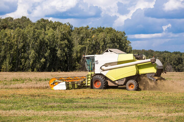 Obraz premium Agricultural industry. A combine harvester harvests from the field. The concept of processing and collection . Rural landscape. Agricultural machinery.
