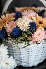 A beautiful, delicate bouquet of flowers in a white wicker basket in the interior. Close-up. Decoration.