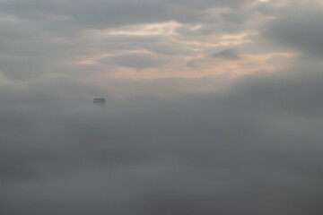A foggy morning view of the Hong Kong skyline, with skyscrapers partially obscured by mist.  Urban landscape, cityscape, Asia, China, fog, haze.