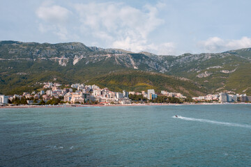 Scenic view of the Becici coastline in Montenegro.  Turquoise waters of the Adriatic Sea meet the sandy beach, with mountains in the background.  Summer vacation destination.