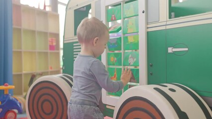 Toddler playing with animal pictures on a toy bus