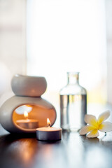 Spa, luxury flower and essential oil with candles on table for wellness retreat, self care treatment or aromatherapy. Space, zen salon or empty room with tranquil display or natural products to relax