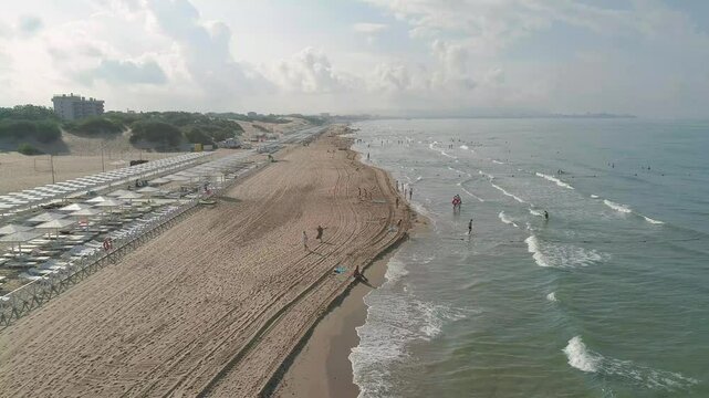 Beach with a lot of people and a boat in the water. The sky is cloudy and the water is green. The Black Sea coast in Anapa at the height of the summer season.