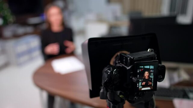 Modern camera with a display recording a speech of a Caucasian brunette. Blogger shooting content for blog. Close up.