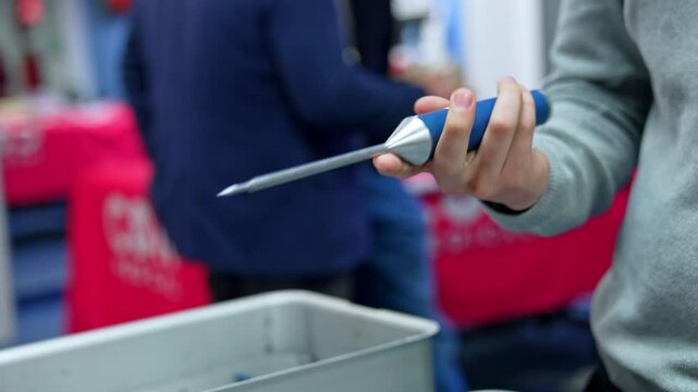 Male hand holding and turning a medical tool. Unrecognized student displaying an instrument for neurosurgery. Close up.