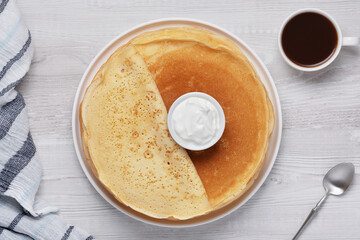 Breakfast with pancakes, cream, and coffee on a wooden table during the morning