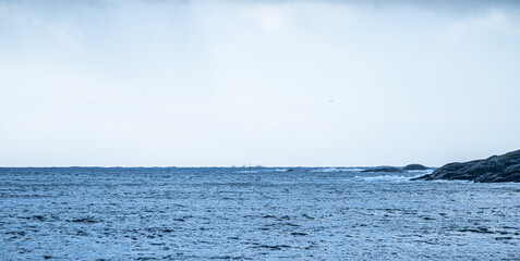 Waved by the coast with a freight ship on the horizon.