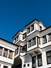 The charming vernacular architecture of Ohrid, with whitewashed buildings and wooden windows, stands out against the vibrant blue sky, showcasing the timeless beauty of this UNESCO-listed town.