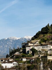 Obraz premium A stunning spring panorama of Berat, Albania, with lush greenery and traditional architecture, framed by snow-capped mountains in the distance, creating a perfect blend of nature and history.