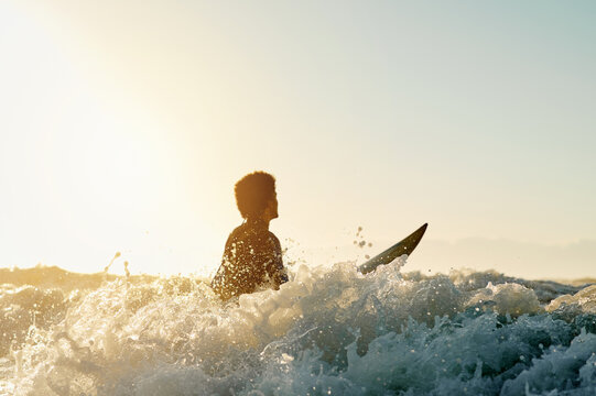 Surf, water splash and blue sky with a sports man in the ocean for training outdoor in nature. Surfing, sea and fitness with a male athlete on his surfboard for his hobby or activity in summer