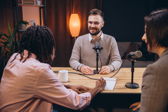 Diverse podcasters recording audio content in a home studio, using microphones and notepad - Powered by Adobe