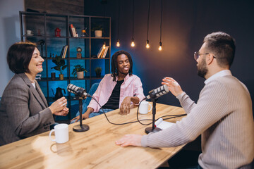 Professional podcast team recording radio show, collaborating and sharing insights during live audio production in soundproofed studio setting