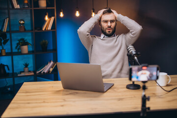 Frustrated podcast host struggling with technical issues during live streaming, hands covering face...