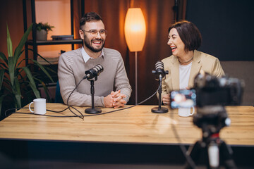 Cheerful podcast hosts laughing while recording inside sleek, contemporary studio, highlighting collaborative creative energy