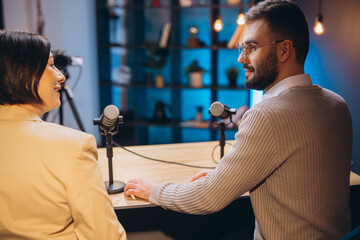 Podcasters discussing animatedly while recording in soundproofed studio, professional microphones...
