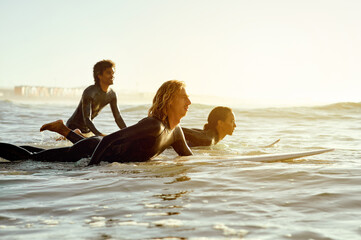 Sunset, adventure and friends surfing at the beach while on a summer vacation, travel or weekend...