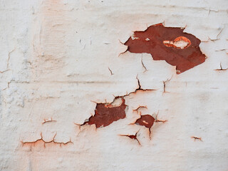 Aufgeplatzter weißer Lack mit rostigen Elementen an einer Hauswand