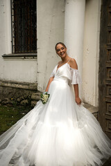 Fototapeta premium bride in a long white dress with a bouquet of lilies of the valley