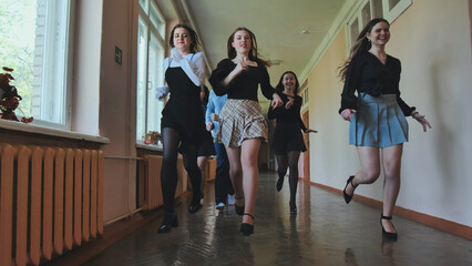Fototapeta premium Happy students running down school hallway after the bell rings, celebrating end of class