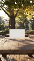 A blank sign on a wooden table in a sunlit park setting.