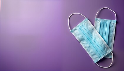 Two light-blue surgical masks lie on vibrant purple surface. Masks positioned diagonally, protective healthcare measures against contagious diseases. Photo represents health, hygiene. Image