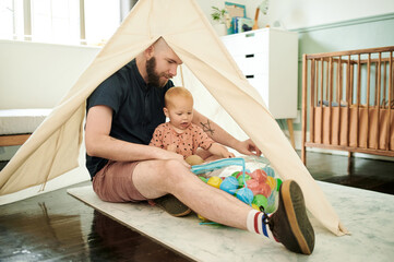 Father, baby and play with balls in tent at home, having fun and bonding together. Child, care and...