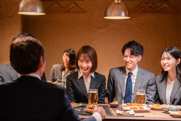 居酒屋で新入社員の歓迎会をするビジネスパーソン