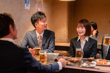 居酒屋で新入社員の歓迎会をするビジネスパーソン