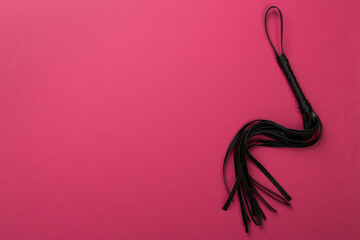 Black whip on color background, top view. BDSM concept