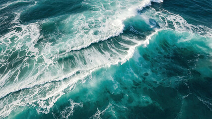 Fototapeta premium aerial view of the ocean waves crashing onto the shore. The water is a deep blue-green color and the waves are white and foamy.