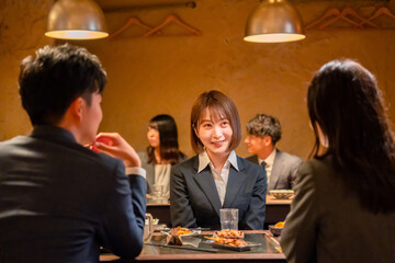 先輩社員と居酒屋で話をするフレッシュな女性