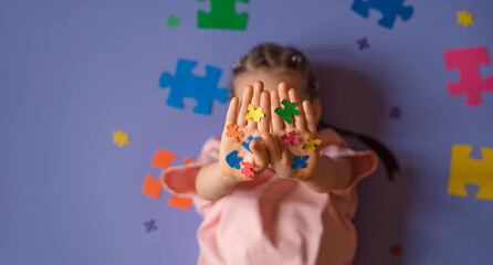 The child's palms are decorated with puzzle pieces in rainbow colors. A banner on the concept of awareness about autism.