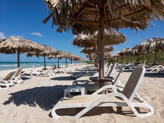 Empty sand beach in Varadero, Cuba. White sunbeds, straw umbrellas and ocean