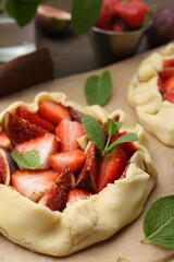 Uncooked galettes with strawberries, figs and mint on table, closeup