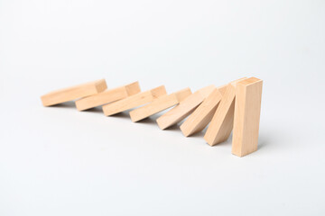 Domino effect. Wooden blocks falling on light background