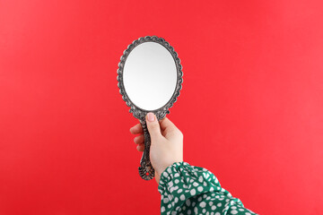 Woman holding beautiful mirror on red background, closeup © New Africa