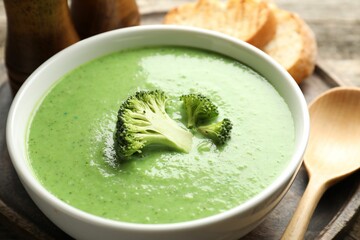 Delicious broccoli cream soup served on wooden table, closeup
