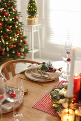 Christmas celebration. Festive table setting with dishware, glasses and decor in room