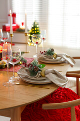 Christmas celebration. Festive table setting with dishware, glasses and decor in room