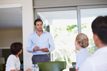 Obraz premium Man, tablet and presentation with business people in boardroom, notes or brainstorming at insurance agency. Person, speaker and touchscreen with group for proposal, meeting or app for feedback at job