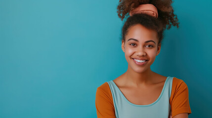 Cheerful young volunteer in casual outfit stands confidently in front of a bright blue background ready for community service outreach