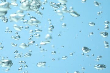 Many water bubbles on light blue background, closeup